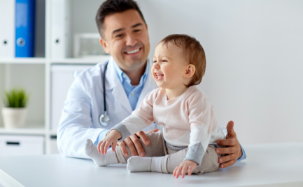 A smiling doctor looking over a happy baby