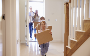 A family carrying moving boxes into their new home
